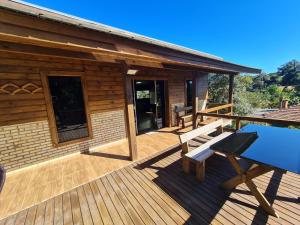 a wooden deck with a bench and a house at Alpes dos anjos Canela rs chalé luxo Wi-Fi SPLIT COZINHA perto do centro in Canela