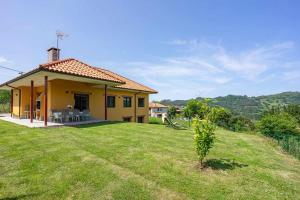 una pequeña casa amarilla con un patio de césped en Casa Rural en Lucena, en Arboleya