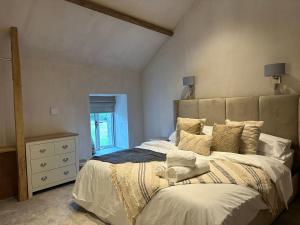 a bedroom with a large bed with white sheets and pillows at Meadow Syke Byre in Penrith