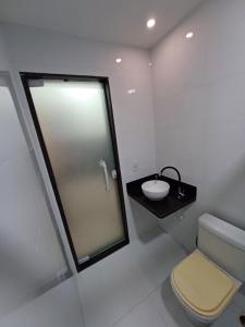 a white bathroom with a sink and a toilet at Loft em Olaria in Rio de Janeiro
