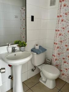 a bathroom with a sink and a toilet and a shower curtain at Departamento NEO IQUIQUE VISTA AL MAR 3 in Iquique