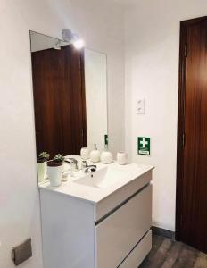 La salle de bains est pourvue d'un lavabo blanc et d'un miroir. dans l'établissement Casa 1-Quinta dos Penedos, à Portalegre