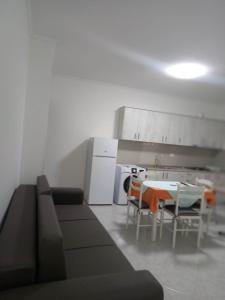 een woonkamer met een bank en een tafel en een keuken bij Appartamento per vacanze estive in Vlorë