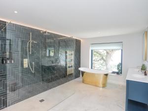 a bathroom with a tub and a wall with black tiles at Ynys Faelog in Menai Bridge