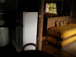 a small bedroom with a bed and a refrigerator at Chiloe, Cabaña la Pincoya in Queilén