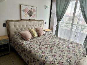 a bedroom with a bed with pillows and a window at Departamento NEO IQUIQUE VISTA AL MAR 3 in Iquique