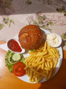 un plato con una hamburguesa y papas fritas y ketchup en Sobe Kraft 1, en Živogošće