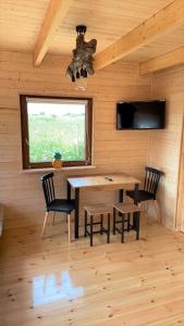 ein Esszimmer mit einem Tisch, Stühlen und einem Fenster in der Unterkunft Domki u strażaka in Jastarnia