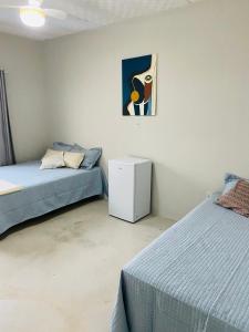 sypialnia z 2 łóżkami i obrazem na ścianie w obiekcie Hanuá Beach House w mieście Guarapari