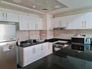 a kitchen with white cabinets and black counter tops at Beautiful 1 Bedroom at Soho Square at Al Saadiyat Island in Abu Dhabi