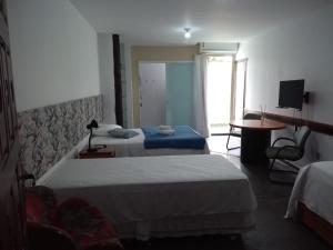 a hotel room with two beds and a table at Hospedagem Praia de Piratininga in Niterói