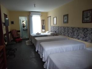 um quarto de hotel com três camas e uma janela em Hospedagem Praia de Piratininga em Niterói