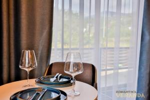 dos copas de vino y platos en una mesa con una ventana en Veranda, en Slavske