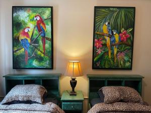 two beds in a room with paintings on the wall at Belize Budget Suites in San Pedro