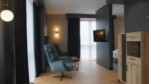 a living room with a blue chair and a television at Artis Loft Hotel in Radziejowice