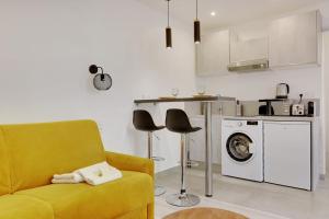 a living room with a yellow couch and a washing machine at Fully renovated studio Buttes-Chaumont in Paris