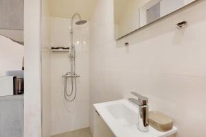 a white bathroom with a shower and a sink at Fully renovated studio Buttes-Chaumont in Paris