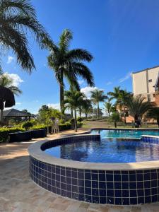 a swimming pool with palm trees in the background at La Palma Hotel Fazenda in Indaiatuba