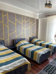 drie bedden in een kamer met gele en blauwe strepen bij CHINAR hotel in Kaji-Say
