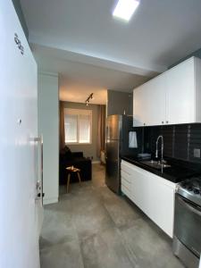 a kitchen with white cabinets and a black refrigerator at Studio - Embaré - Santos, frente ao mar in Santos