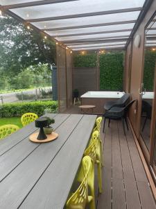 una terraza de madera con mesa y sillas amarillas en BIG BERRY Kolpa - Isabella Premium House, en Gradac