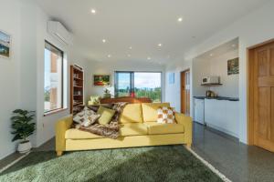 a living room with a yellow couch and a kitchen at Countryview Haven in Tasman
