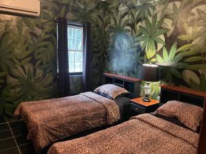 Un dormitorio con 2 camas y una pared con plantas. en Belize Budget Suites en San Pedro