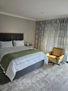 ein Schlafzimmer mit einem großen Bett und einem Stuhl in der Unterkunft Intuthuzelo on Bramleigh in East London