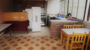 uma cozinha com um frigorífico, uma mesa e cadeiras em Nery Lodging em Huaraz