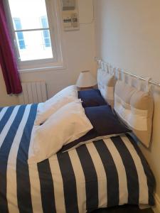 a bed with striped sheets and pillows in a room at Les falaises d Etretat Etretat hypercentre duplex 50m de la mer & parking in Étretat