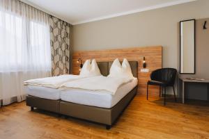 een slaapkamer met een groot bed en een stoel bij Die Pension Galle in Arnoldstein