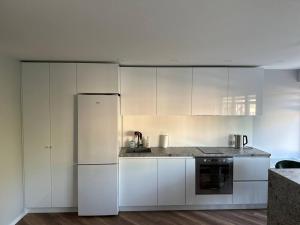 a kitchen with white cabinets and a refrigerator at Sun apartment in Jūrmala