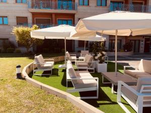 grupa krzeseł i parasoli na trawniku w obiekcie Apartamentos Esperanza del Mar w mieście Portonovo