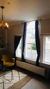 una sala de estar con una ventana con cortinas azules y una silla en Willoughby Apartment, en Bath