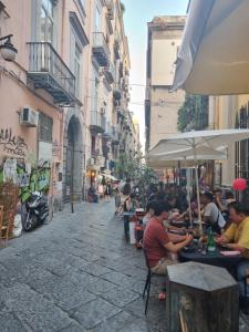 eine Gruppe von Menschen, die an Tischen auf einer Straße sitzen in der Unterkunft Uànema House in Neapel