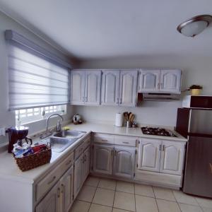 a kitchen with white cabinets and a sink and a refrigerator at Divino depa remodelado, tranquilo y centrico. in Ciudad Juárez