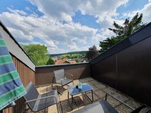 eine Terrasse mit 2 Stühlen und einem Tisch auf dem Balkon in der Unterkunft Ferienhaus-Schönwald, 2 Schlafzimmer, Küche, Dachterrasse, Balkon App24 in Schönwald