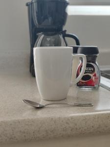 a white coffee cup sitting on a counter with a spoon at Divino depa remodelado, tranquilo y centrico. in Ciudad Juárez