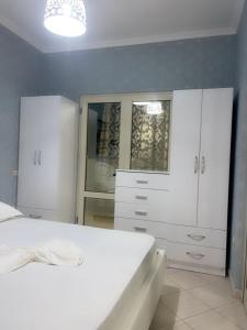a bedroom with a white bed and a dresser at Mirela’s Apartment City Center in Tirana