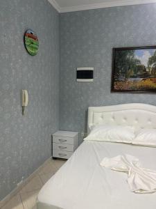 a bedroom with a white bed and a clock on the wall at Mirela’s Apartment City Center in Tirana