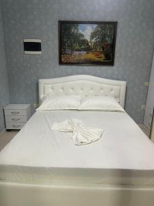 a white bed in a bedroom with a picture on the wall at Mirela’s Apartment City Center in Tirana