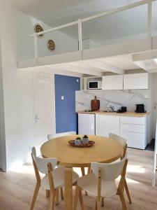 a kitchen with a wooden table and white chairs at Cocoon Urbain Nantais in Nantes