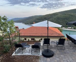 a group of chairs and an umbrella on a patio at Apartments Zahtila - Berto in Rabac