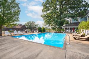 una piscina en un patio con sillas y árboles en White Rose Inns & Motel en Wisconsin Dells