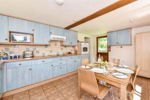 a kitchen with blue cabinets and a wooden table at Taylors Copse Cottage by Inspire Stays in Petersfield