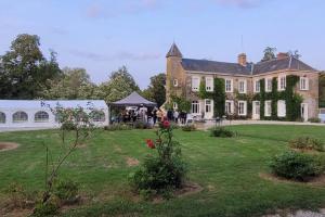 a group of people standing in front of a large house at Domaine de Beaucamp in Châtelraould-Saint-Louvent