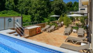 a swimming pool with chairs and umbrellas next to a pool at Apartamentos Trisquel in Sanxenxo
