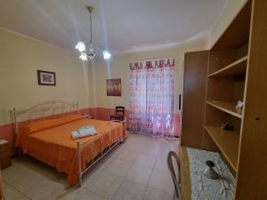 sypialnia z łóżkiem z pomarańczową pościelą i oknem w obiekcie Casa Sibarys 20 mt dalla Stazione piano terra w mieście Sibari