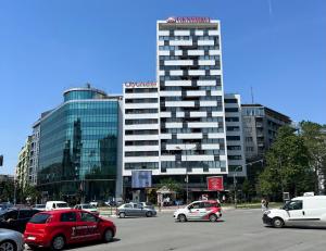 een groot gebouw met auto's geparkeerd op een parkeerplaats bij Midtown Boutique Apartment in Novi Sad