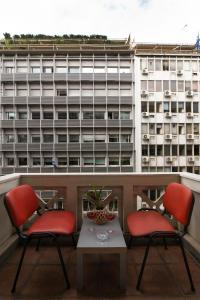 two chairs and a table on a balcony with a building at Alpha 1 in Athens